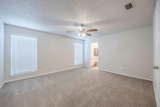 unfurnished bedroom featuring a textured ceiling, ceiling fan, ensuite bathroom, and light carpet