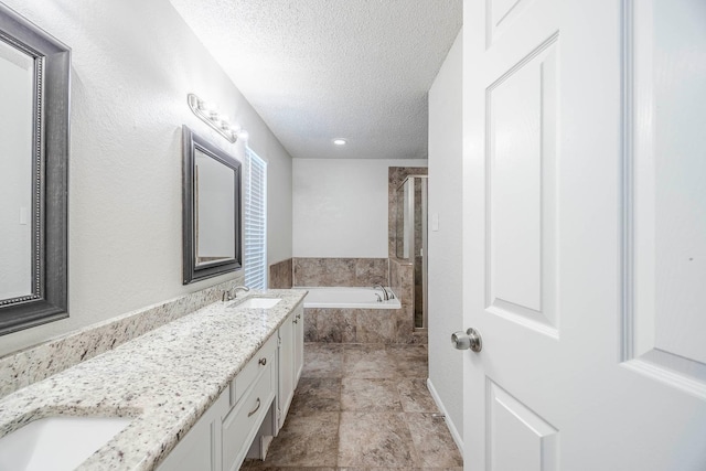 bathroom with vanity, a textured ceiling, and independent shower and bath