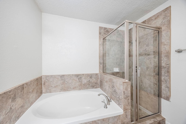 bathroom featuring plus walk in shower and a textured ceiling