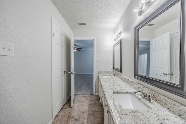 bathroom featuring ceiling fan, vanity, and a textured ceiling