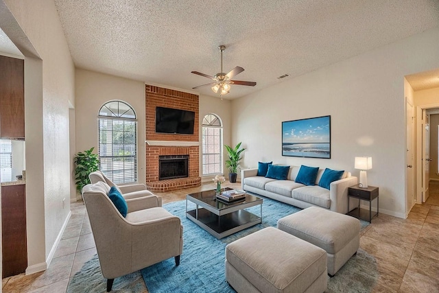 living room featuring ceiling fan, light tile patterned floors, a textured ceiling, and a brick fireplace