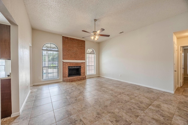 unfurnished living room with ceiling fan, a fireplace, light tile patterned flooring, and a textured ceiling