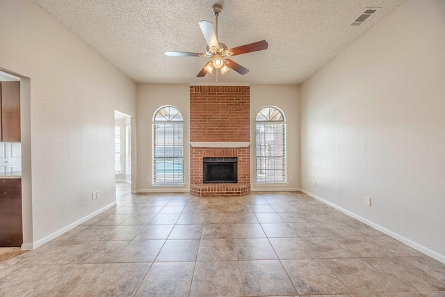 unfurnished living room with a fireplace, a textured ceiling, ceiling fan, and light tile patterned flooring