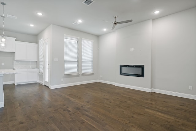 unfurnished living room featuring ceiling fan and dark wood-type flooring