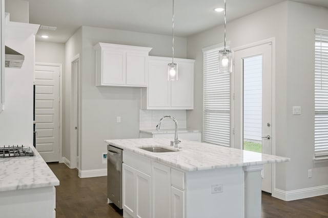 kitchen featuring a center island with sink, sink, pendant lighting, and light stone countertops