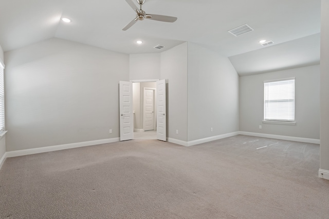 spare room with vaulted ceiling, ceiling fan, and light colored carpet