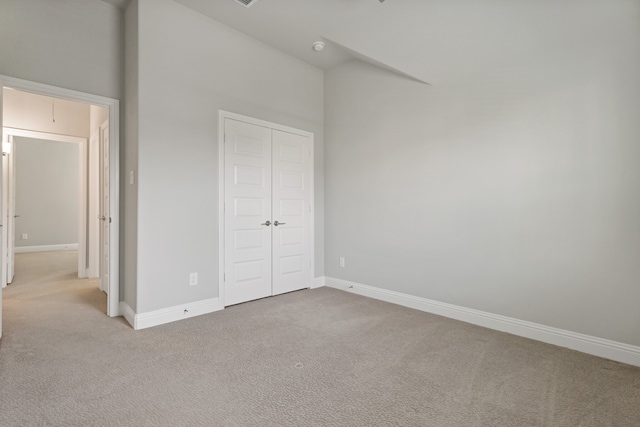 unfurnished bedroom with light carpet and a closet