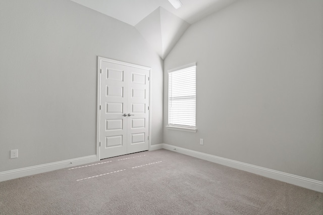 spare room featuring carpet and vaulted ceiling