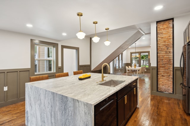 kitchen featuring dark hardwood / wood-style flooring, an island with sink, dishwasher, pendant lighting, and sink