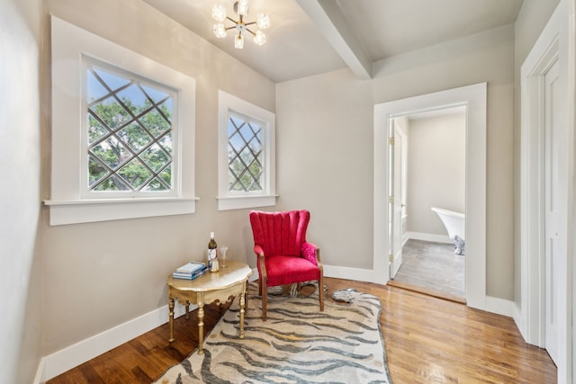 sitting room featuring beamed ceiling, a notable chandelier, and light wood-type flooring