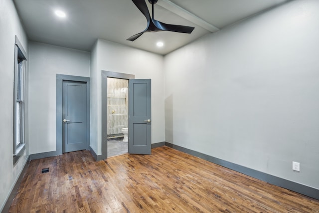 unfurnished bedroom with dark wood-type flooring, ceiling fan, and ensuite bath