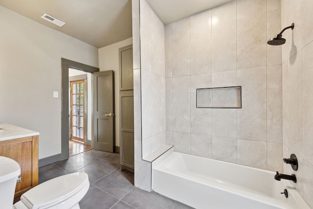 full bathroom featuring toilet, tiled shower / bath combo, vanity, and tile patterned flooring