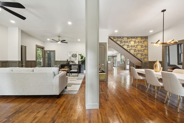 living room featuring dark wood-type flooring and ceiling fan with notable chandelier