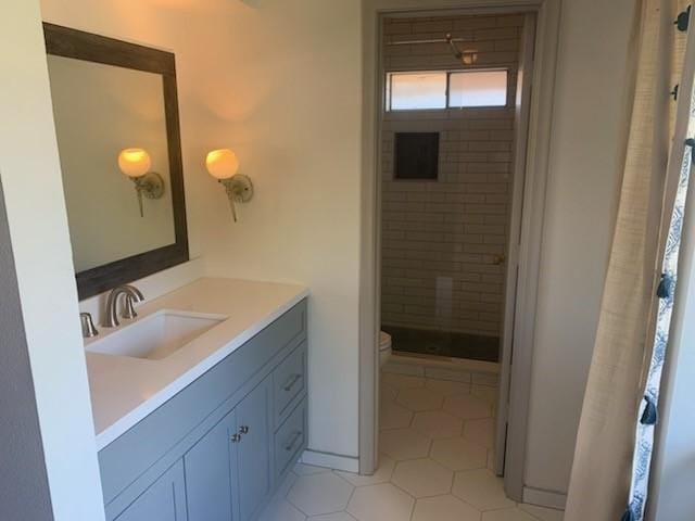 bathroom with vanity, tile patterned flooring, toilet, and a tile shower