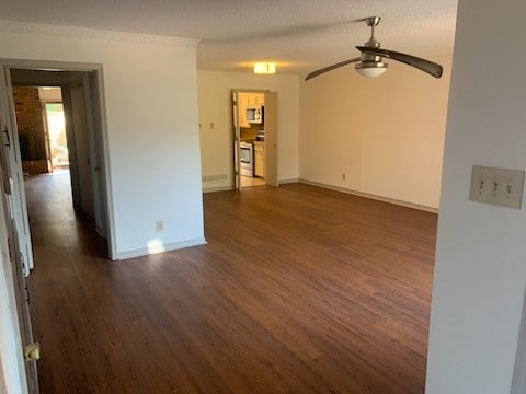 unfurnished living room with ceiling fan, dark hardwood / wood-style floors, and a textured ceiling