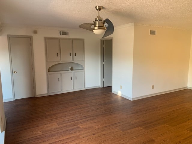 unfurnished living room featuring ceiling fan, dark hardwood / wood-style flooring, and a textured ceiling