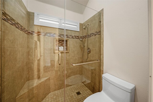 bathroom with a shower with door and toilet