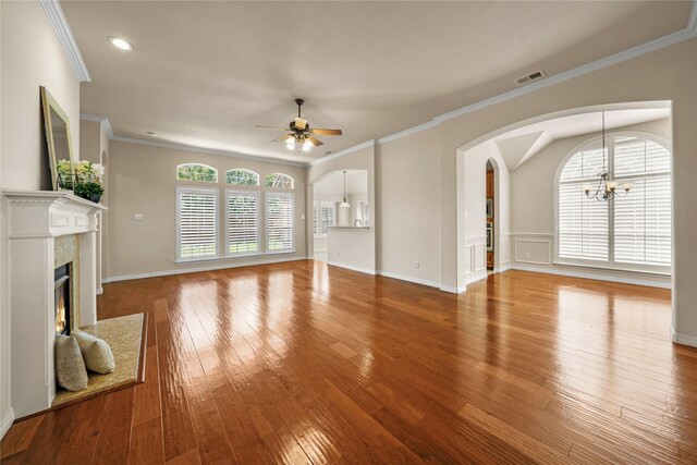 unfurnished living room featuring a premium fireplace, ceiling fan with notable chandelier, crown molding, and hardwood / wood-style floors