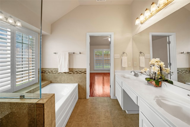 bathroom featuring dual vanity, a bathing tub, hardwood / wood-style flooring, and vaulted ceiling