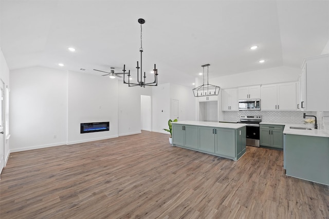 kitchen with sink, hanging light fixtures, stainless steel appliances, a center island, and vaulted ceiling