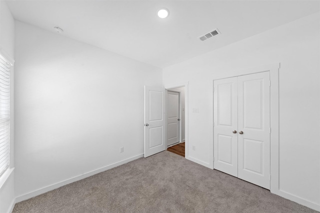 unfurnished bedroom with light carpet and a closet