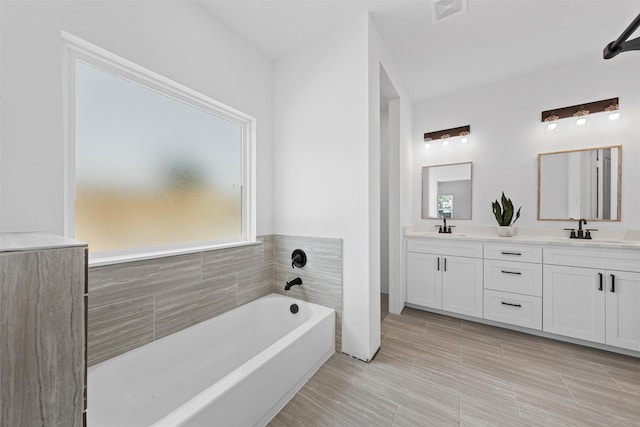 bathroom featuring a washtub, vanity, and tile walls