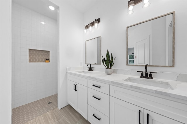 bathroom with a tile shower and vanity