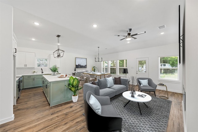 living room with plenty of natural light, light hardwood / wood-style floors, and ceiling fan with notable chandelier