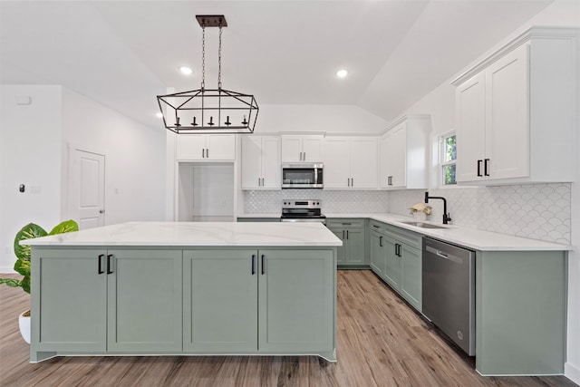 kitchen with stainless steel appliances, vaulted ceiling, decorative light fixtures, light hardwood / wood-style floors, and a kitchen island