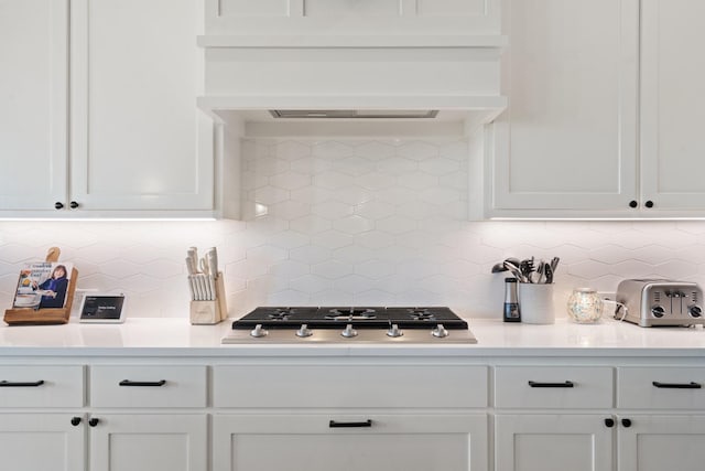 kitchen with white cabinetry, decorative backsplash, custom exhaust hood, and stainless steel gas stovetop