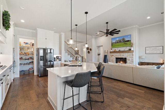 kitchen with white cabinetry, sink, a breakfast bar area, stainless steel fridge, and a kitchen island with sink