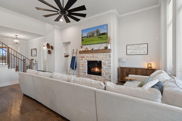 living room featuring an inviting chandelier, ornamental molding, dark hardwood / wood-style floors, and a stone fireplace