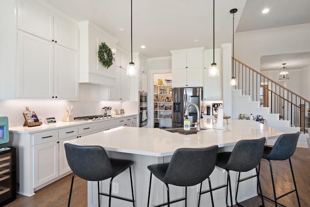 kitchen with appliances with stainless steel finishes, a large island, hanging light fixtures, and white cabinets