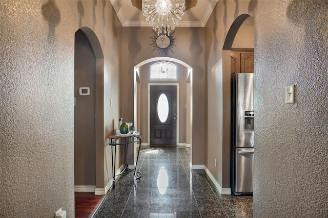 foyer entrance with a high ceiling, an inviting chandelier, and ornamental molding