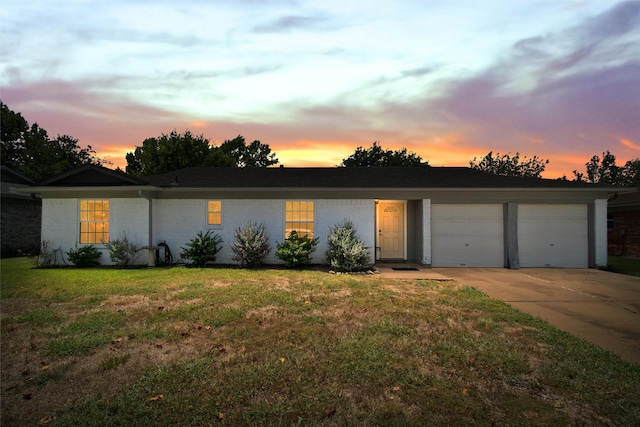 ranch-style home with a garage and a lawn