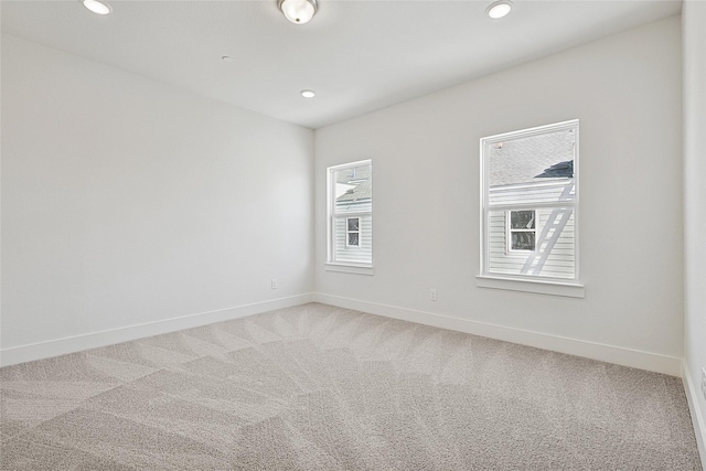 unfurnished room with light colored carpet, recessed lighting, and baseboards