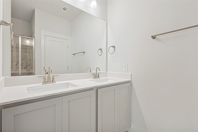 full bath with double vanity, visible vents, a shower stall, and a sink