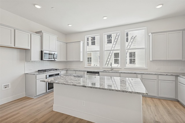 kitchen featuring a center island, stainless steel appliances, backsplash, and a sink