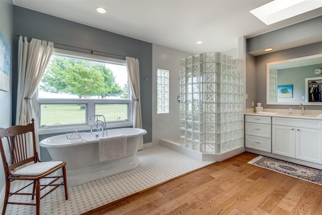 bathroom with hardwood / wood-style floors, vanity, independent shower and bath, and a skylight