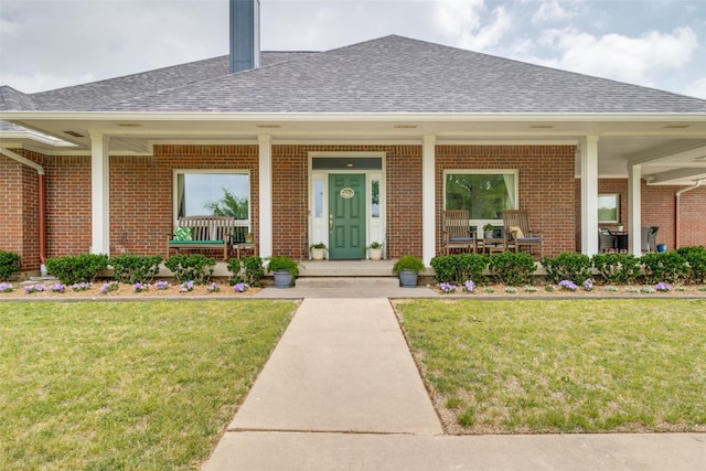 view of exterior entry featuring a porch and a lawn