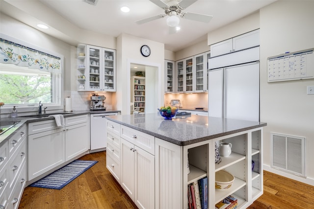 kitchen featuring a center island, backsplash, dark hardwood / wood-style floors, dishwashing machine, and white cabinetry