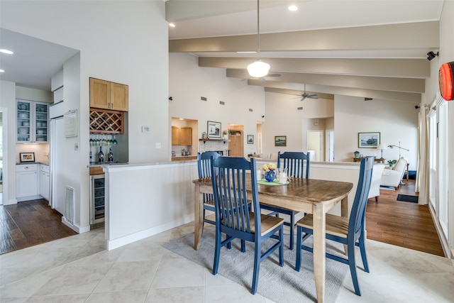 dining space with lofted ceiling, indoor bar, ceiling fan, light tile patterned floors, and beverage cooler