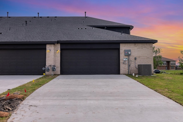 exterior space featuring a garage, a lawn, and central air condition unit