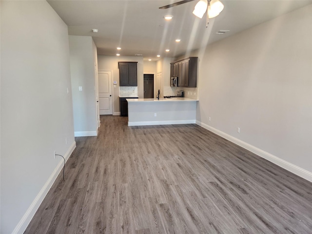 unfurnished living room with ceiling fan, sink, and dark hardwood / wood-style flooring