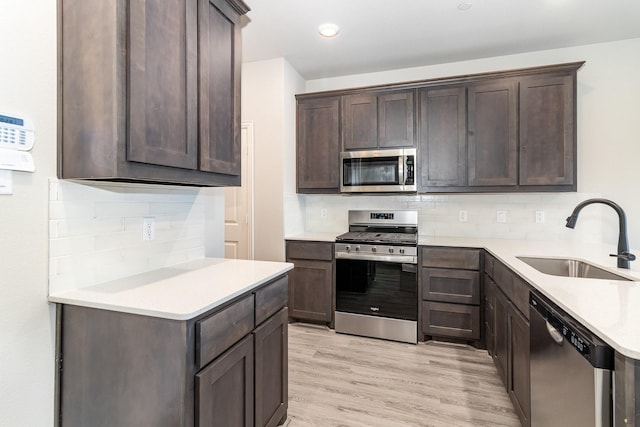 kitchen featuring appliances with stainless steel finishes, light hardwood / wood-style floors, sink, and dark brown cabinets