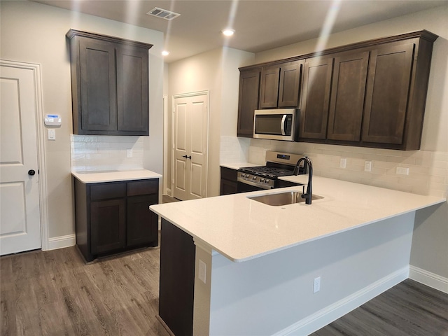 kitchen with sink, hardwood / wood-style floors, stainless steel appliances, and kitchen peninsula