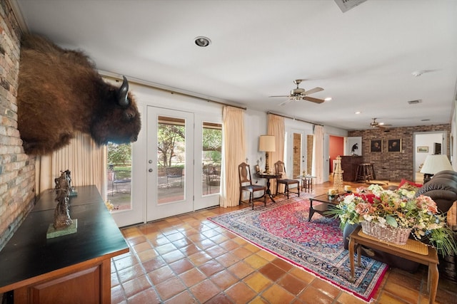 tiled living room featuring french doors, ceiling fan, and brick wall