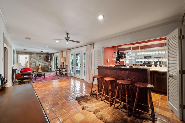 bar featuring french doors, ceiling fan, ornamental molding, light tile patterned flooring, and brick wall