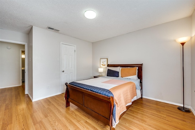 bedroom featuring a textured ceiling and light hardwood / wood-style flooring