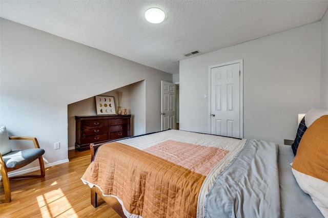 bedroom featuring a textured ceiling and light hardwood / wood-style flooring